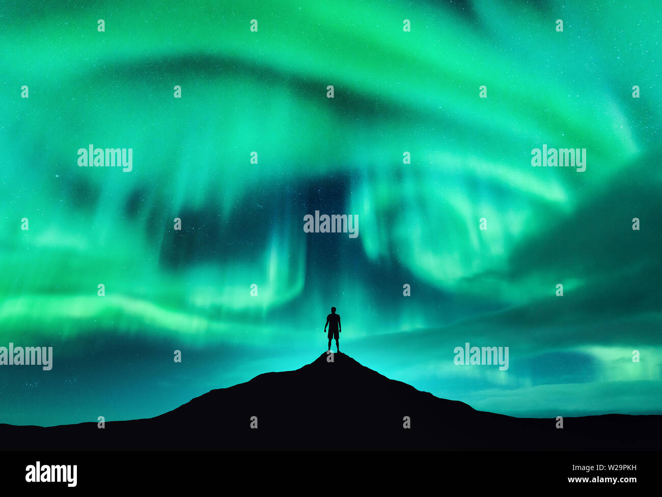 Aurora borealis and silhouette of a man on the mountain peak Stock Photo