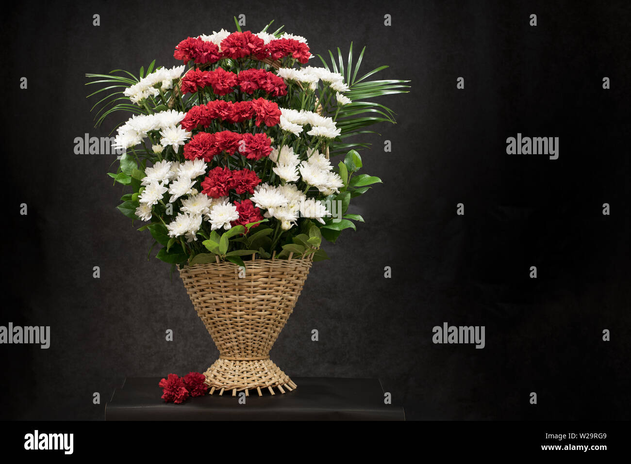 Ritual funeral basket with flowers on a black background.The flower