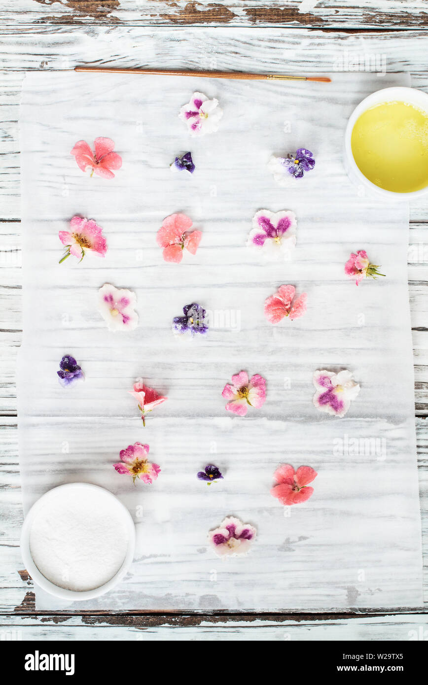 Ingredients for making homemade sugared or crystallized edible flowers on a white wooden rustic table. Image shot for above. Stock Photo