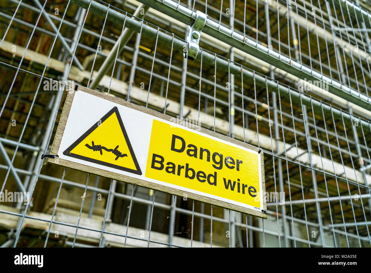 Danger barbed wire safety sign on metal fence Stock Photo