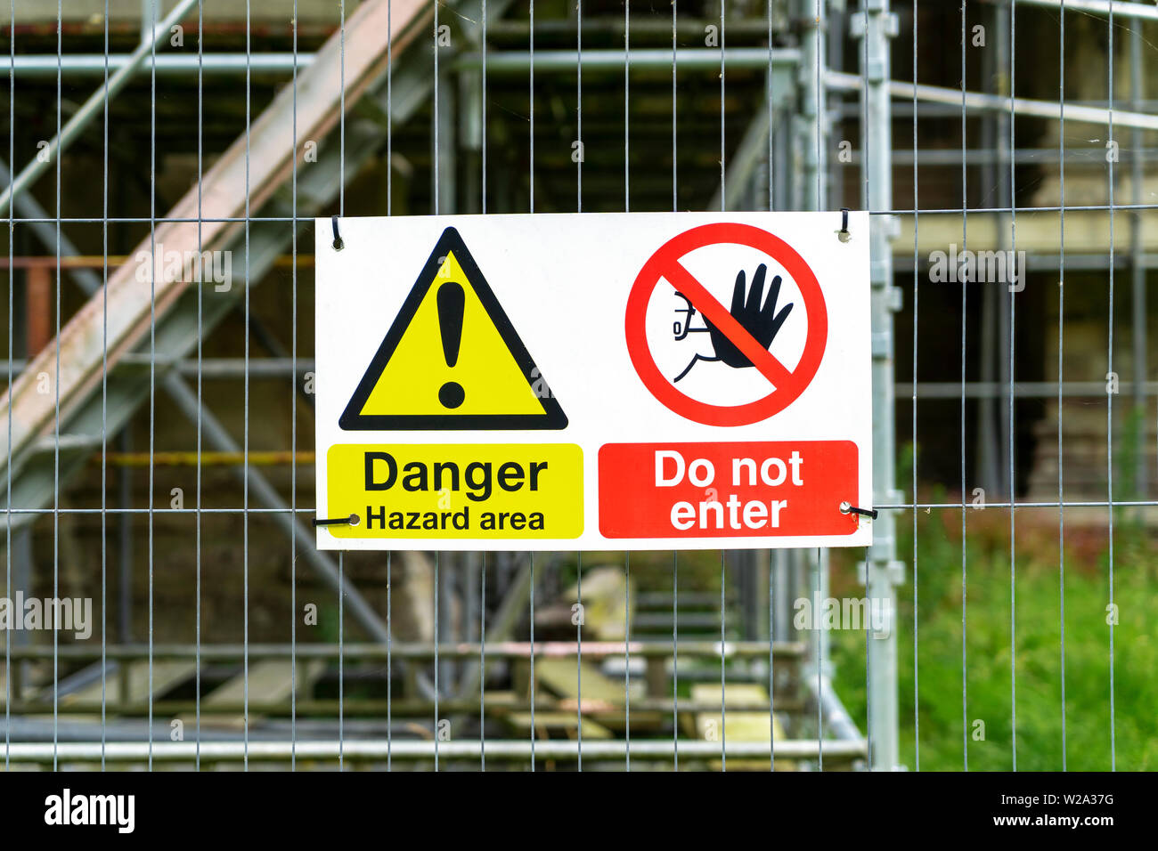 Hazard warning safety signs on metal fencing outside of building site Stock Photo