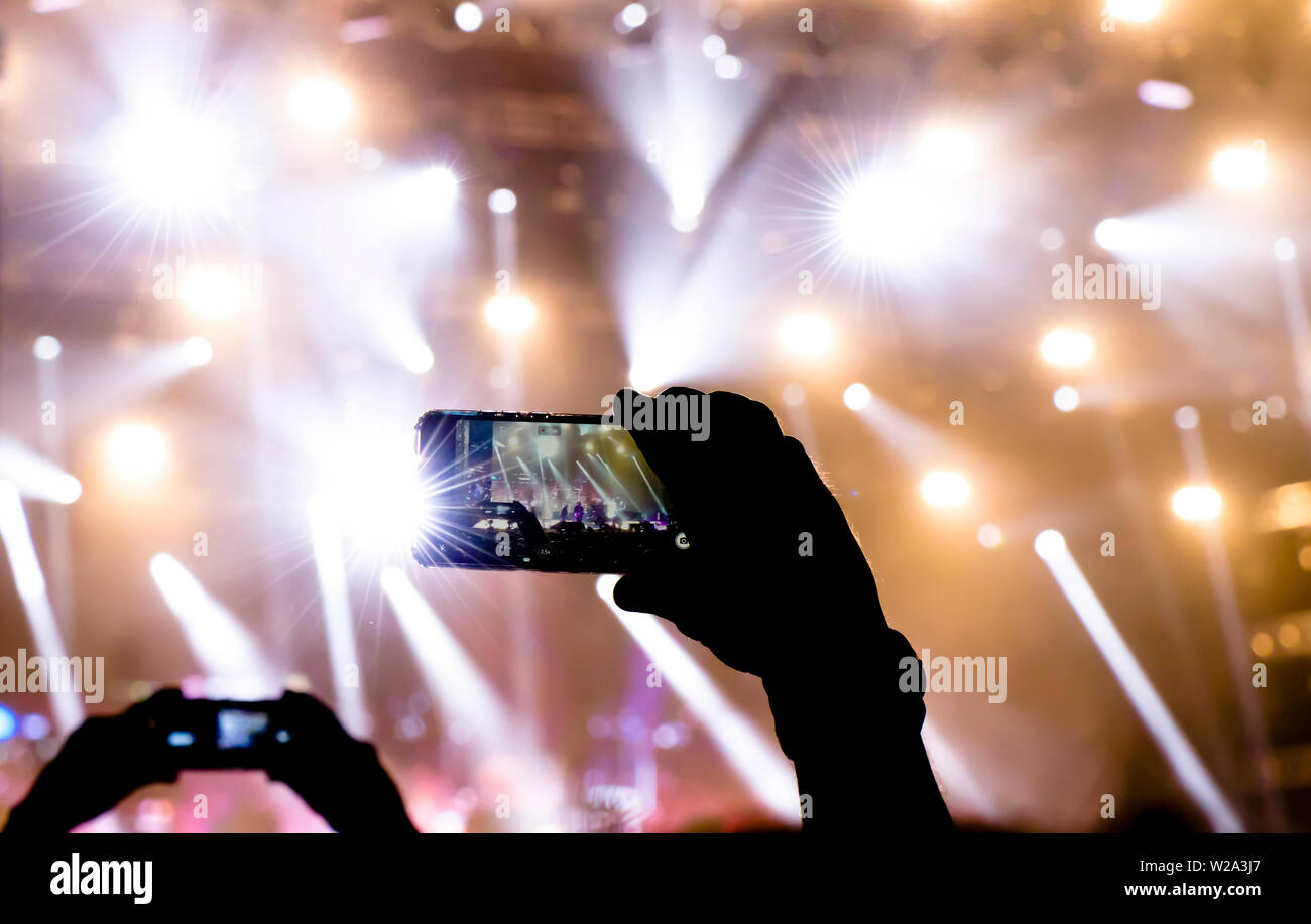 Collecting digital memory is loosing capability of being present, silhouette of people shooting the concert event with mobile phones Stock Photo