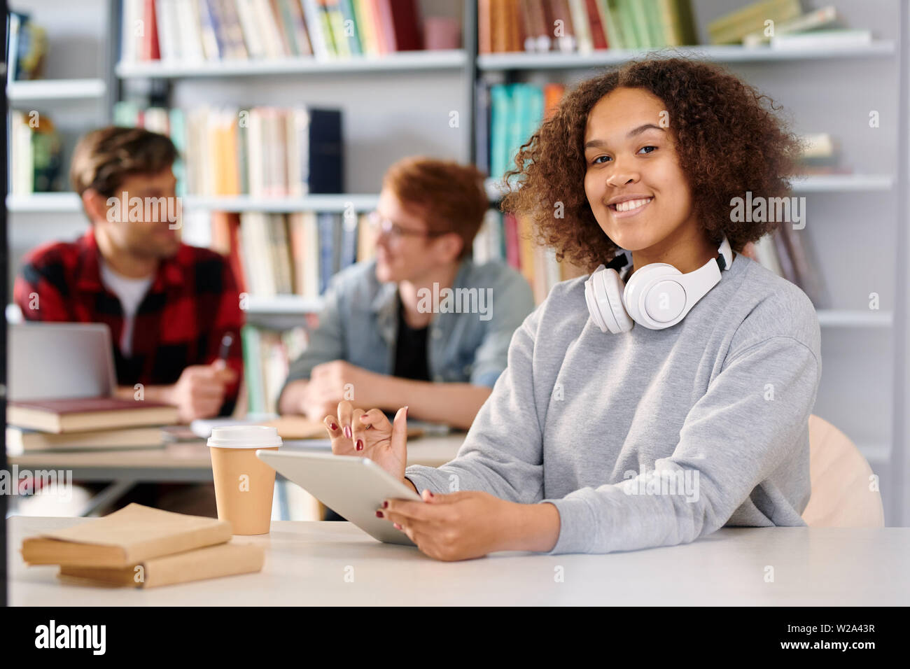 Young cheerful student with tablet getting ready for exam Stock Photo