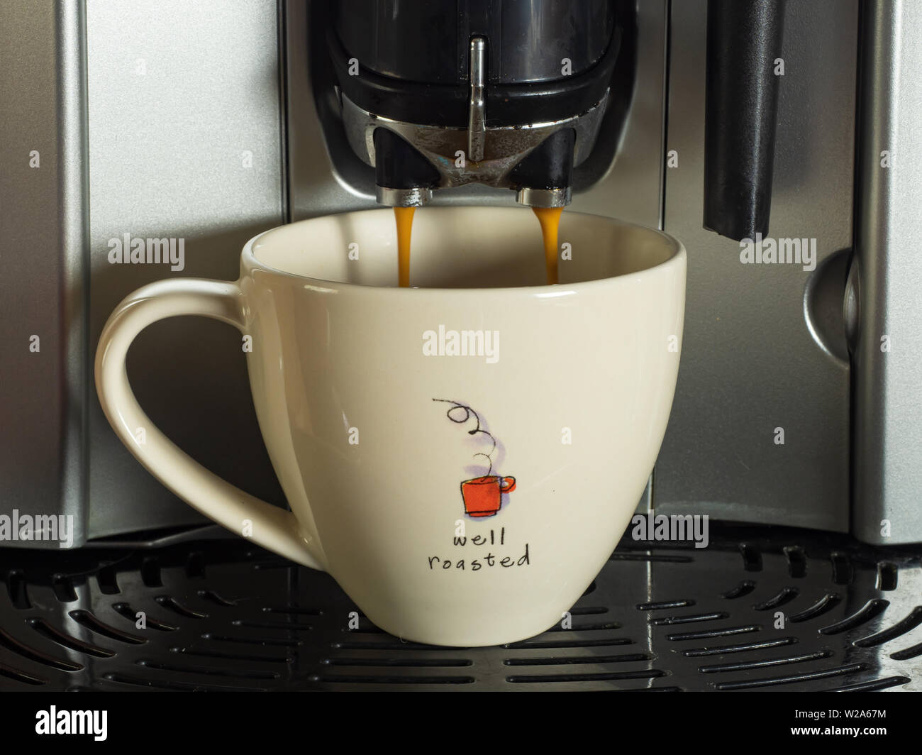 Coffee being dispensed from a bean to cup coffee machine in to a white cup Stock Photo