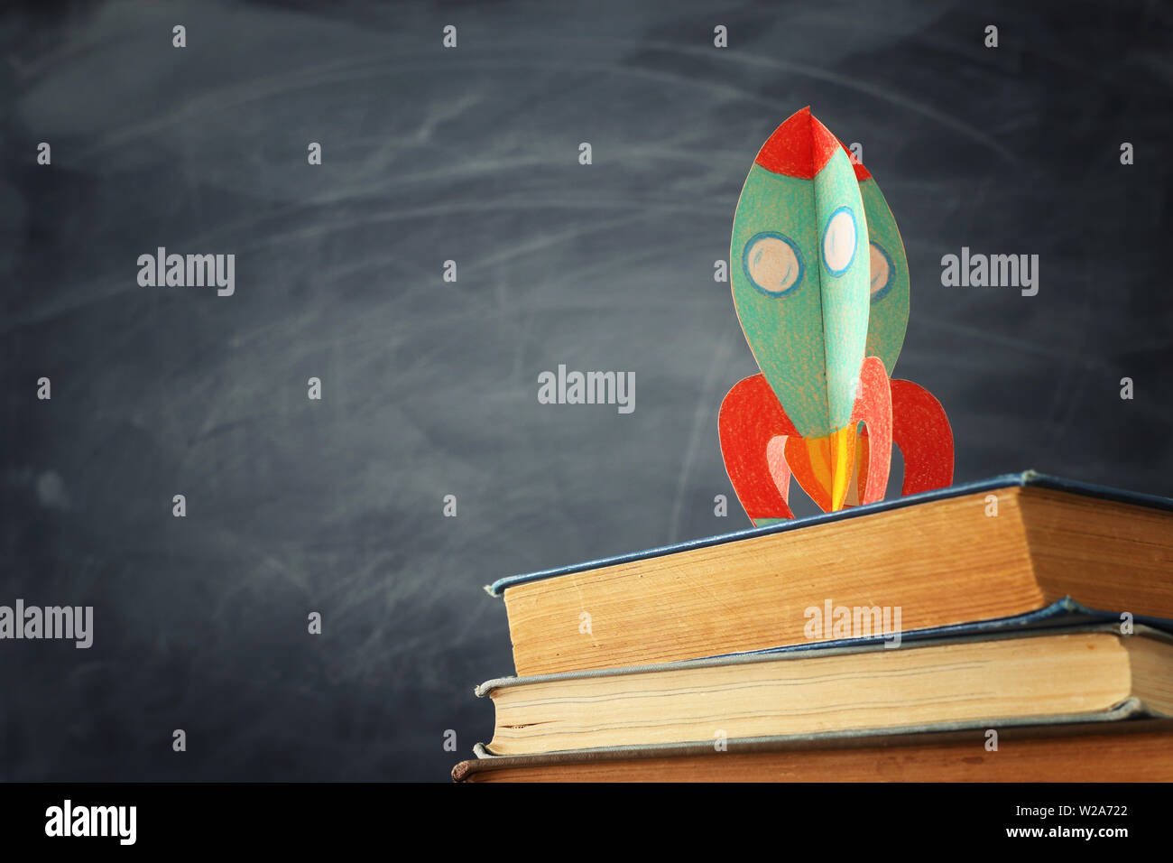 education and back to school concept. cardboard rocket over books in ...