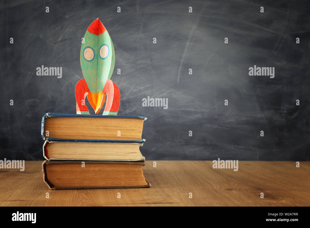 education and back to school concept. cardboard rocket over books in ...
