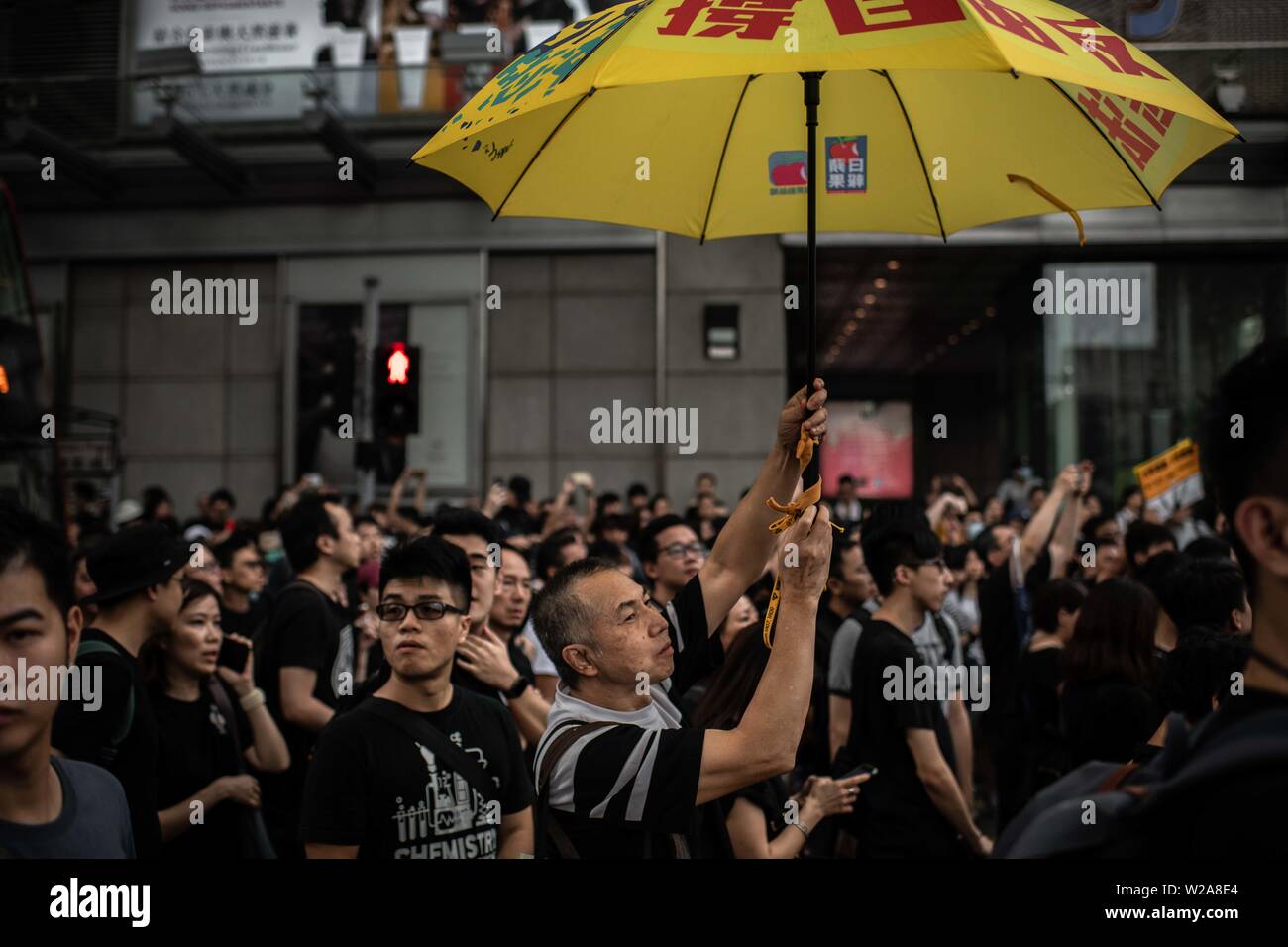 A man holds a yellow umbrella as a symbol of Hong Kong democracy during the protest against the extradition law to China. Stock Photo