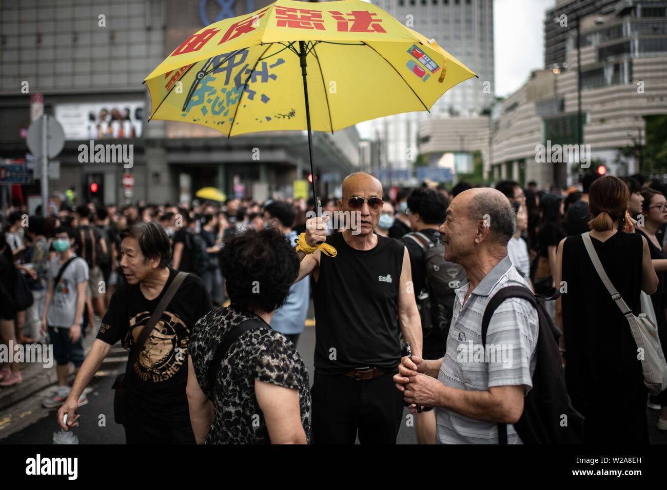 A man holds a yellow umbrella as a symbol of Hong Kong democracy during the protest against the extradition law to China. Stock Photo