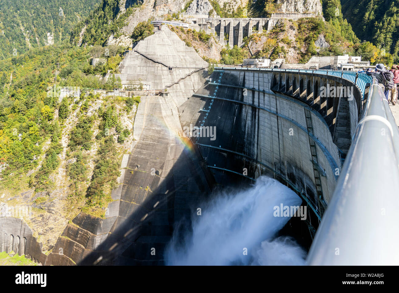 Closeup View Of Water Turbines Are Producing Electricity At Power Plant. Panorama View Of Hydro Power Station And People On The Kurobe Lake Dam,Toyama Stock Photo
