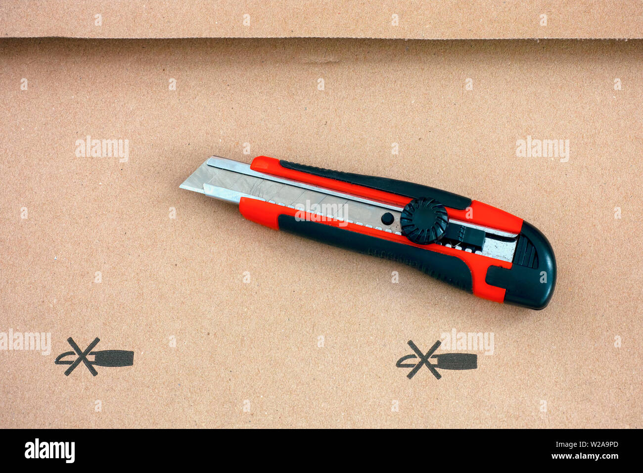 Red paper knife on cardboard with Do not open with a knife sign. Close