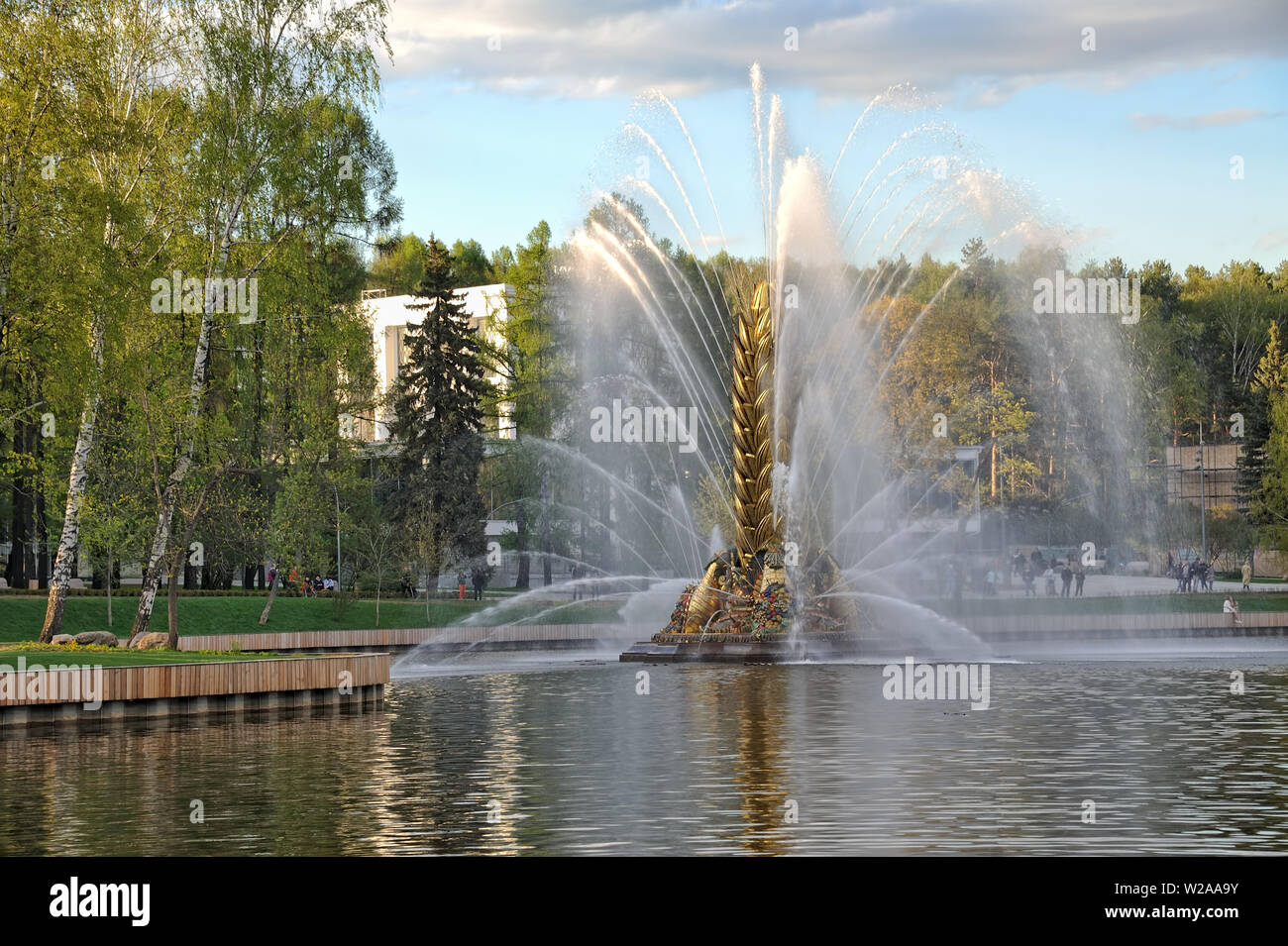 = Golden Spike Fountain Framed by Birch Trees at Sunset =  Beautiful view on one of the most spectacular fountains at VDNKh “The Golden Spike” in the Stock Photo