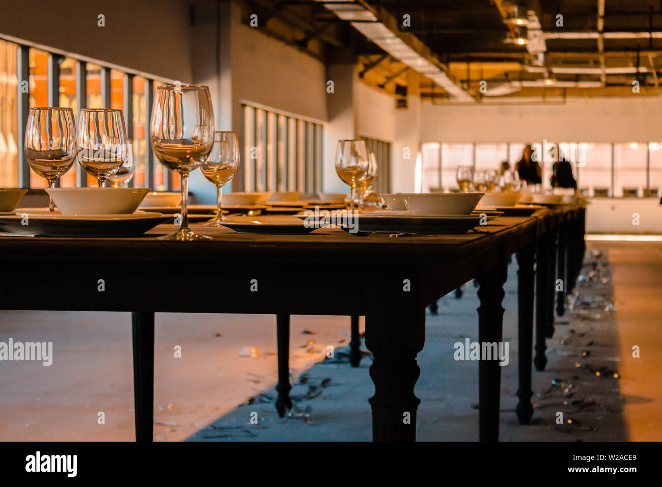 Shot of the long table that is set with dishes and many have fallen and broken Stock Photo