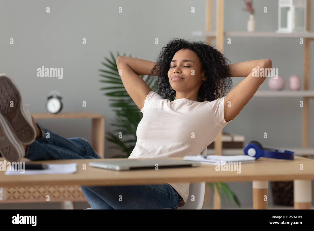 Happy african girl student relaxing finished study sit at desk Stock Photo