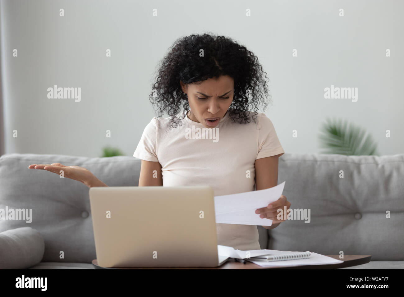 Angry stressed african girl reading bad news in mail letter Stock Photo