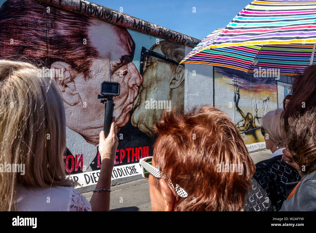 Brezhnev Honecker kiss, four ladies watching it, East Side Wall Gallery, Berlin Wall Tourists Germany Friedrichshain city street Stock Photo