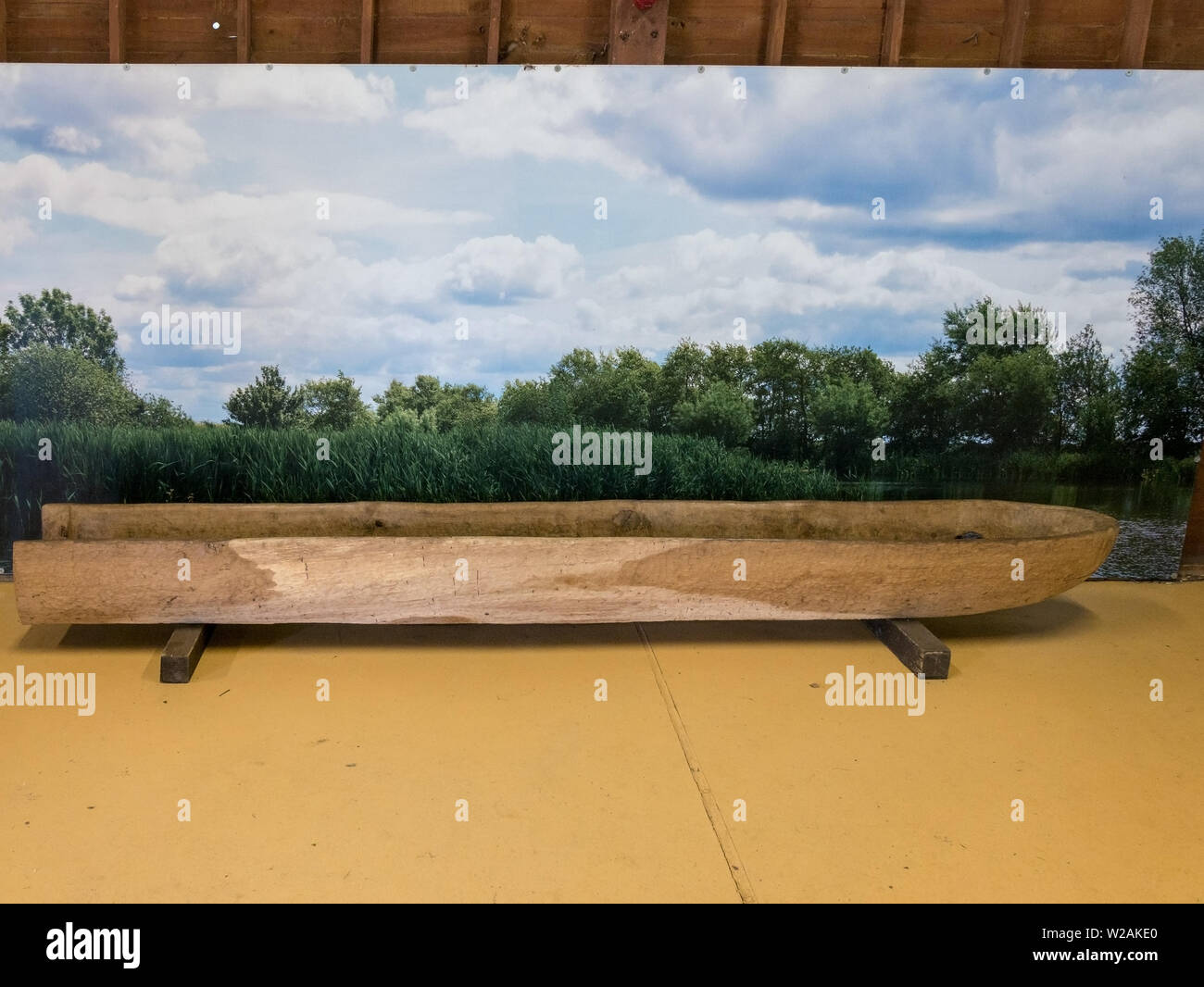 Reconstructed Bronze age log boat in front of painted display board, Flag Fen, Peterborough, Cambridgeshire, England, UK Stock Photo