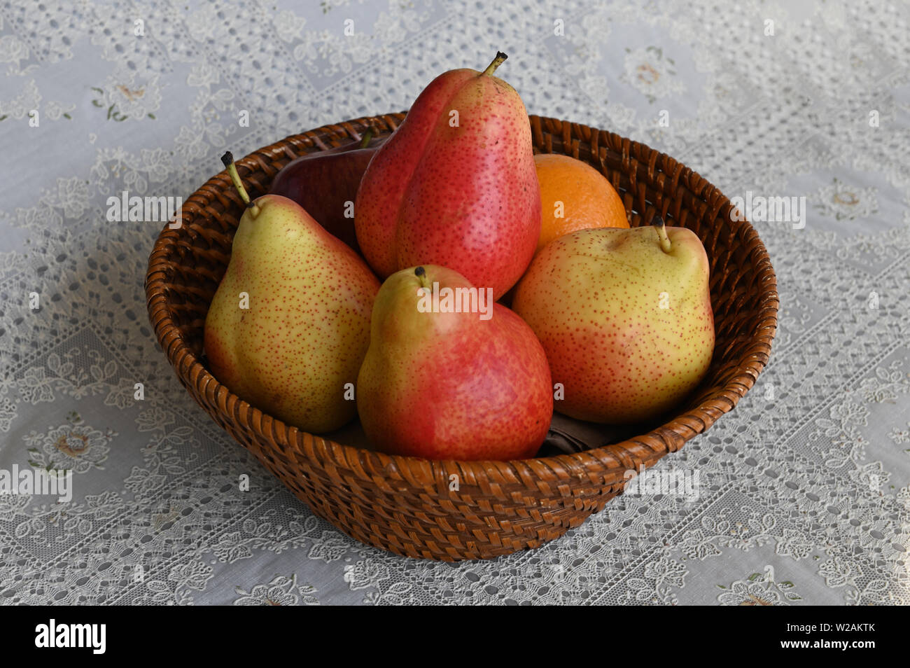 red and yellow pears in basket on white table cloth Stock Photo