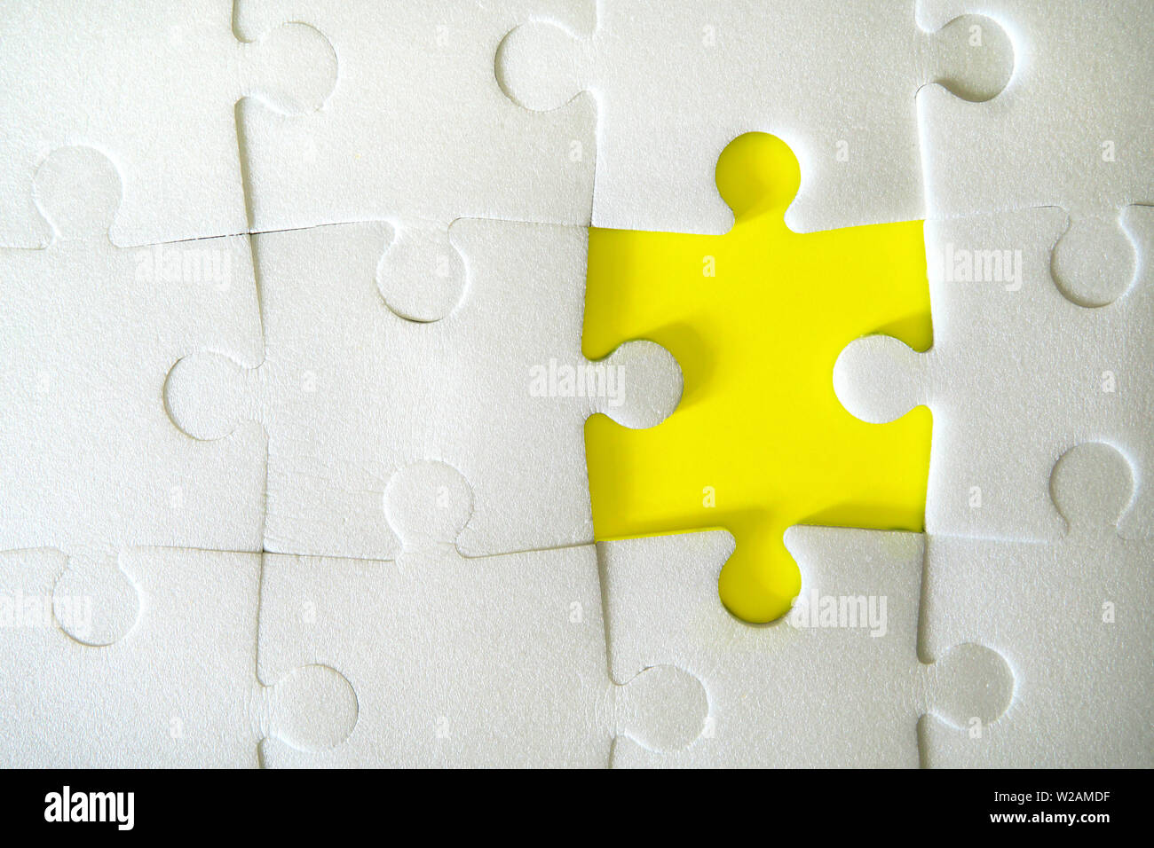 Multiple white puzzle pieces put together without one piece. View from above. Stock Photo