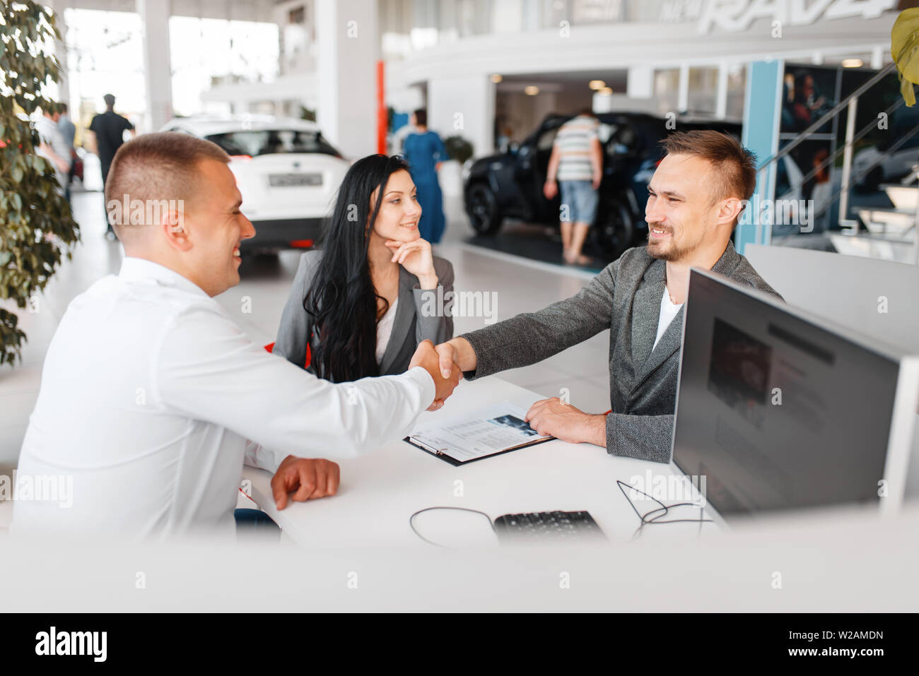 Manager And A Couple Make Out The Sale Of A New Car In The