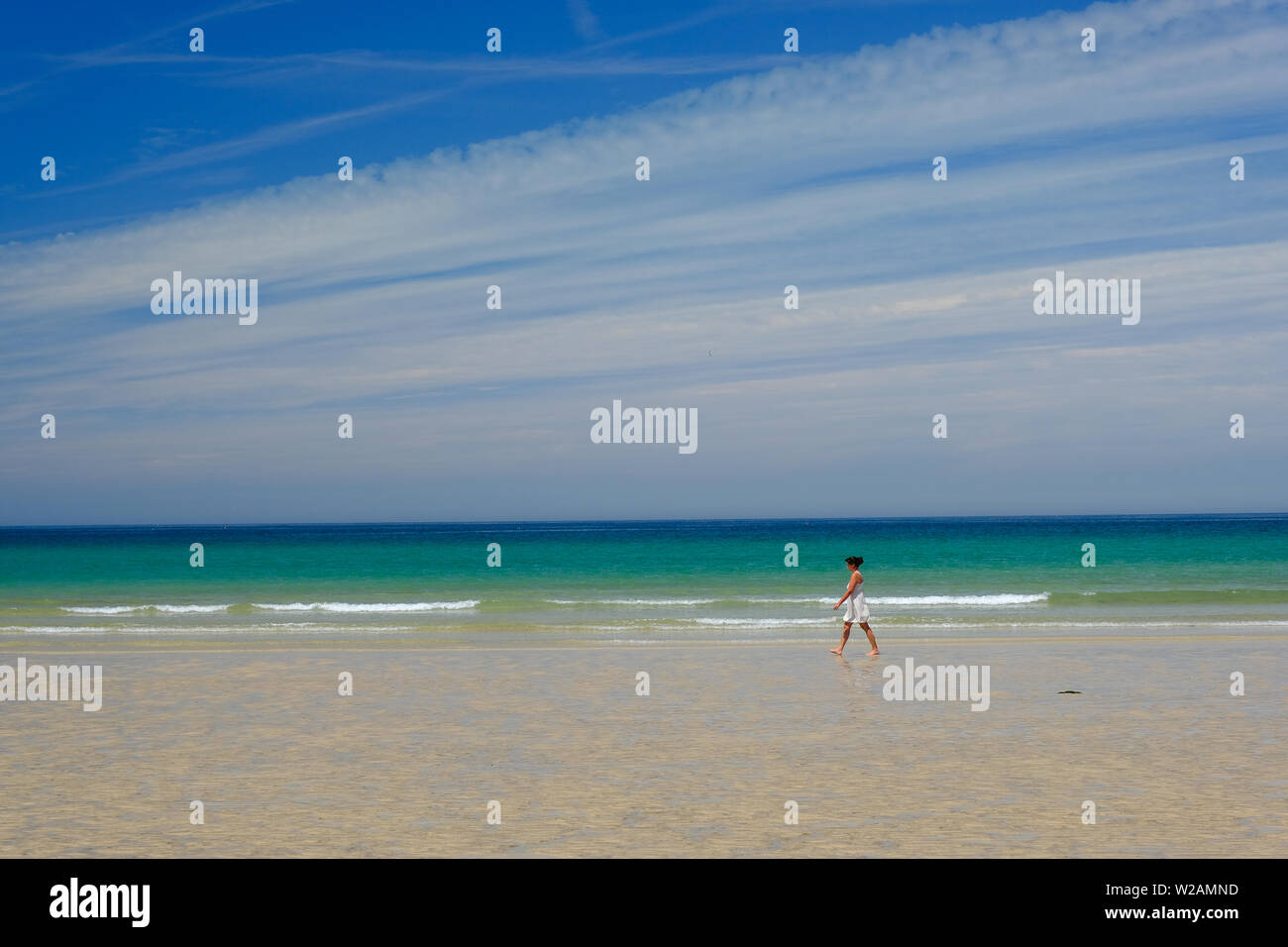 Woman walking along the sandy beach at Godrevy in Cornwall on a summer's day Stock Photo