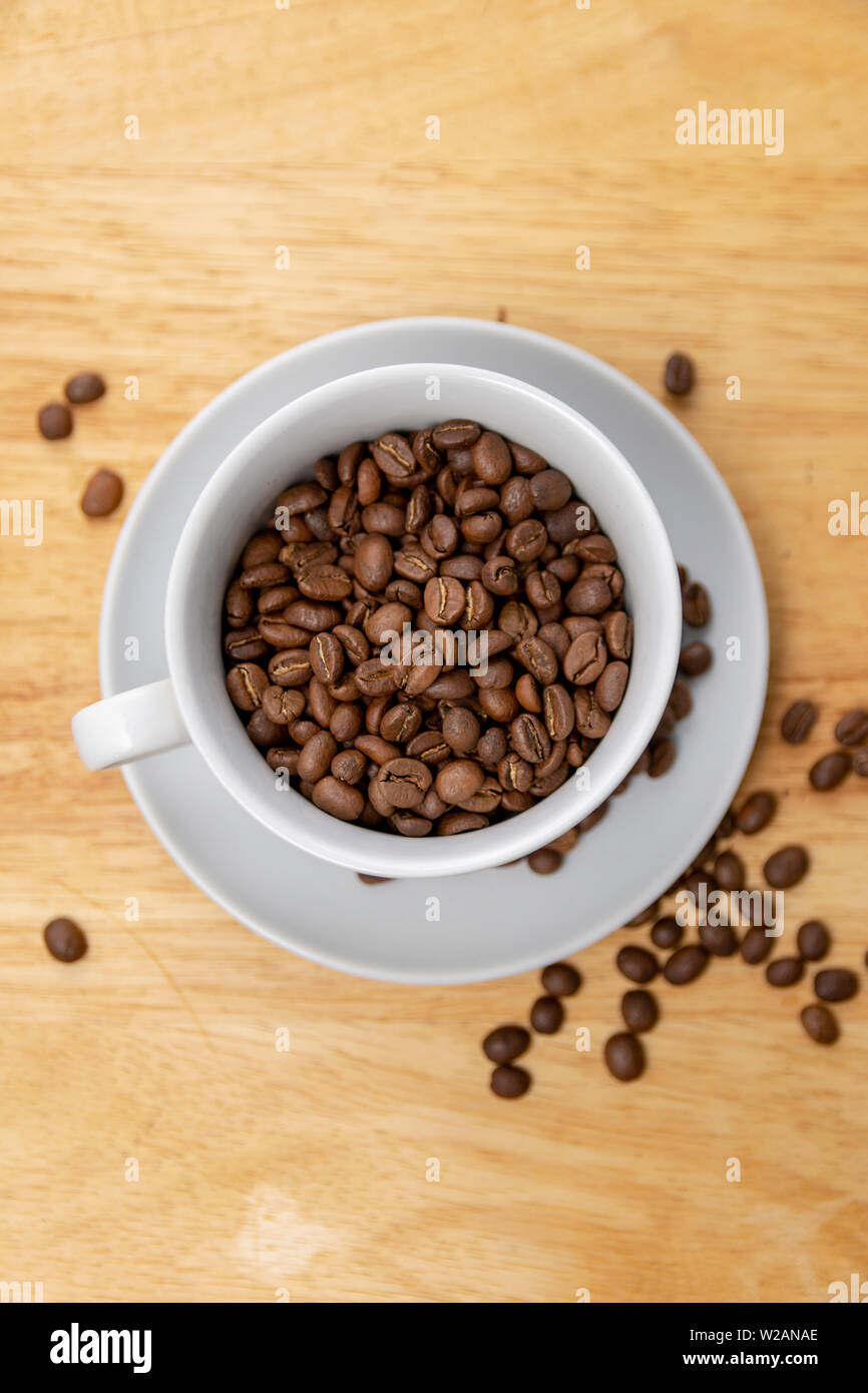 Coffee Beans in a Cup and Saucer on a Wooden Table Stock Photo