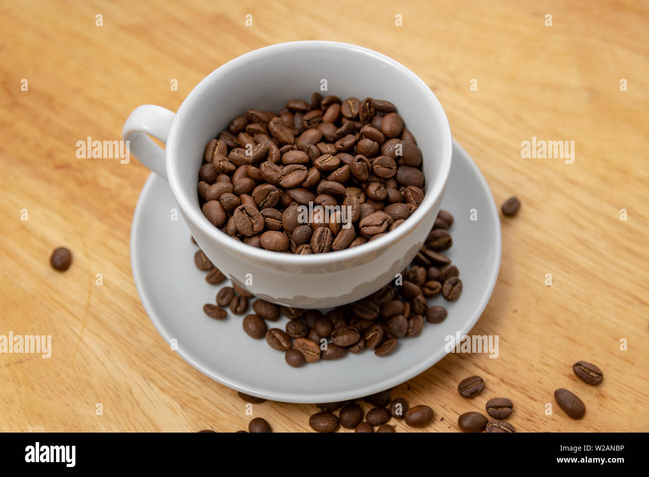 Coffee Beans in a Cup and Saucer on a Wooden Table Stock Photo