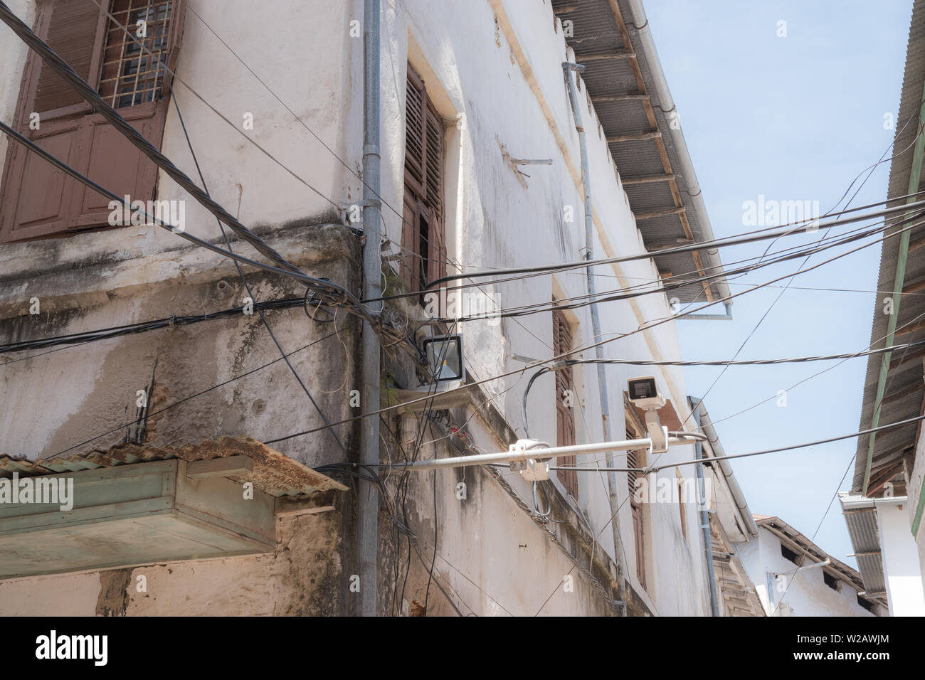 Juxtaposition of old vs new. Electrical wires between two buildings in Stone Town,Zanzibar. Stock Photo