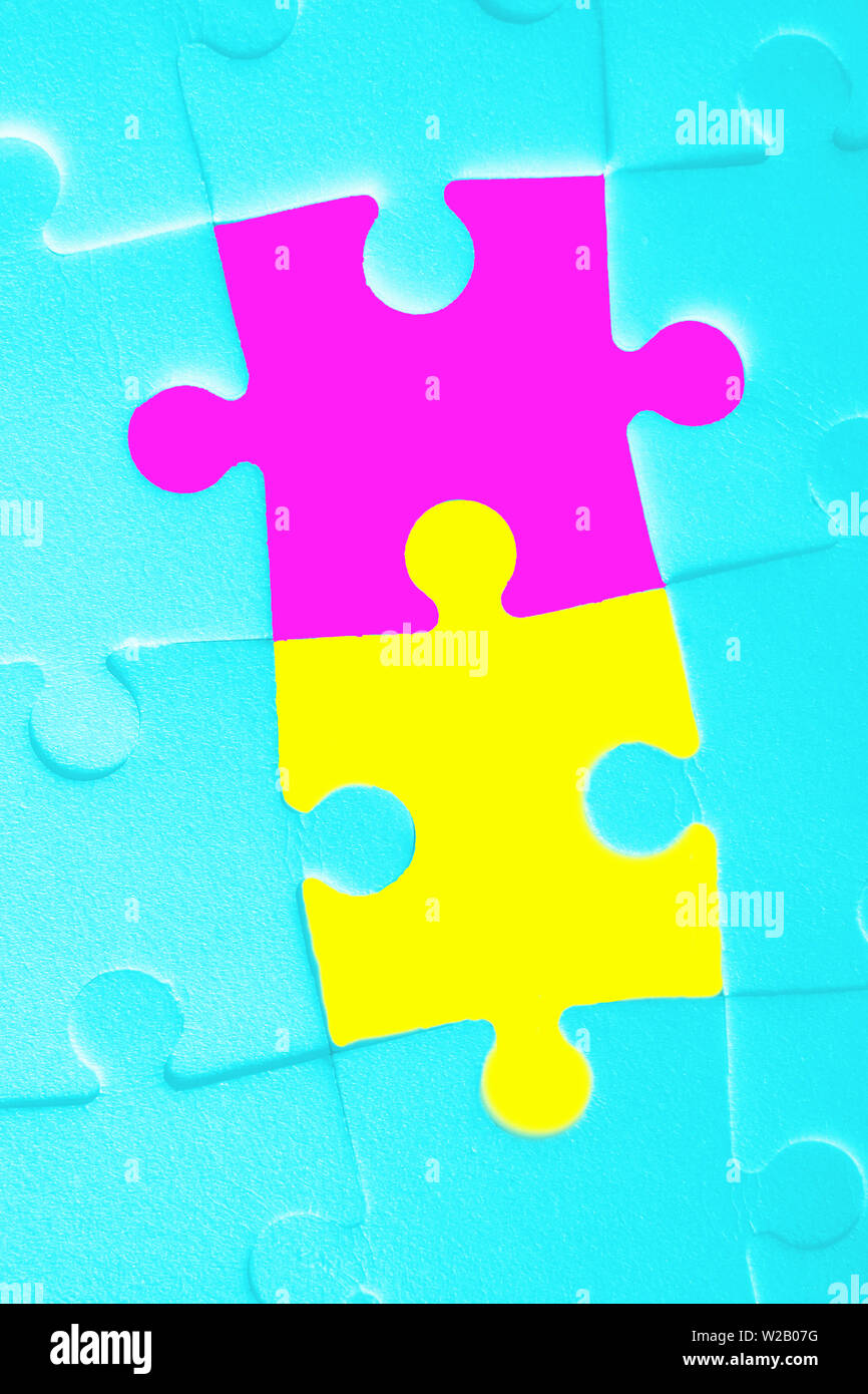 Multiple white puzzle pieces put together with two bright pieces. View from above. Stock Photo