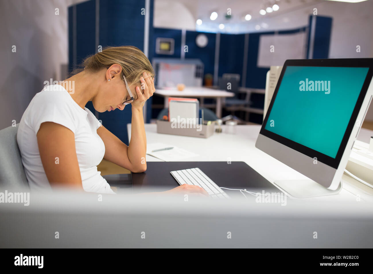 Overworked/burnout office employe at her computer, suffering from a ...