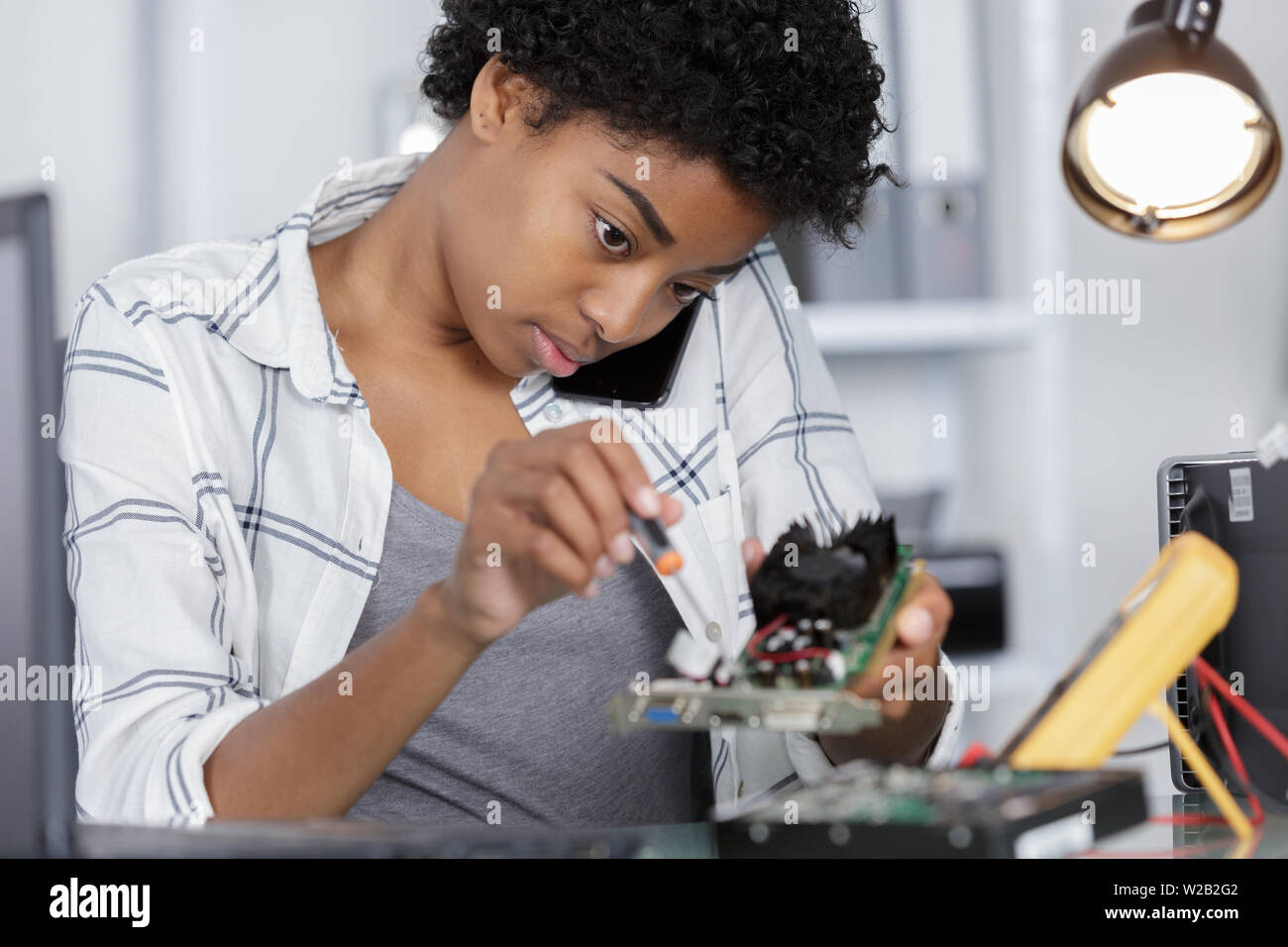 female on the phone fixing a computer Stock Photo