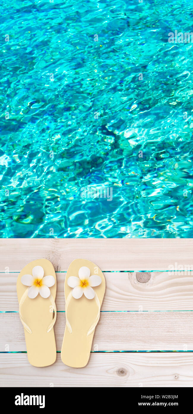 Flip flops with tiare flowers on the wooden planks decking above the sea blurred background. Tropical island paradise.  Bright turquoise ocean water. Stock Photo