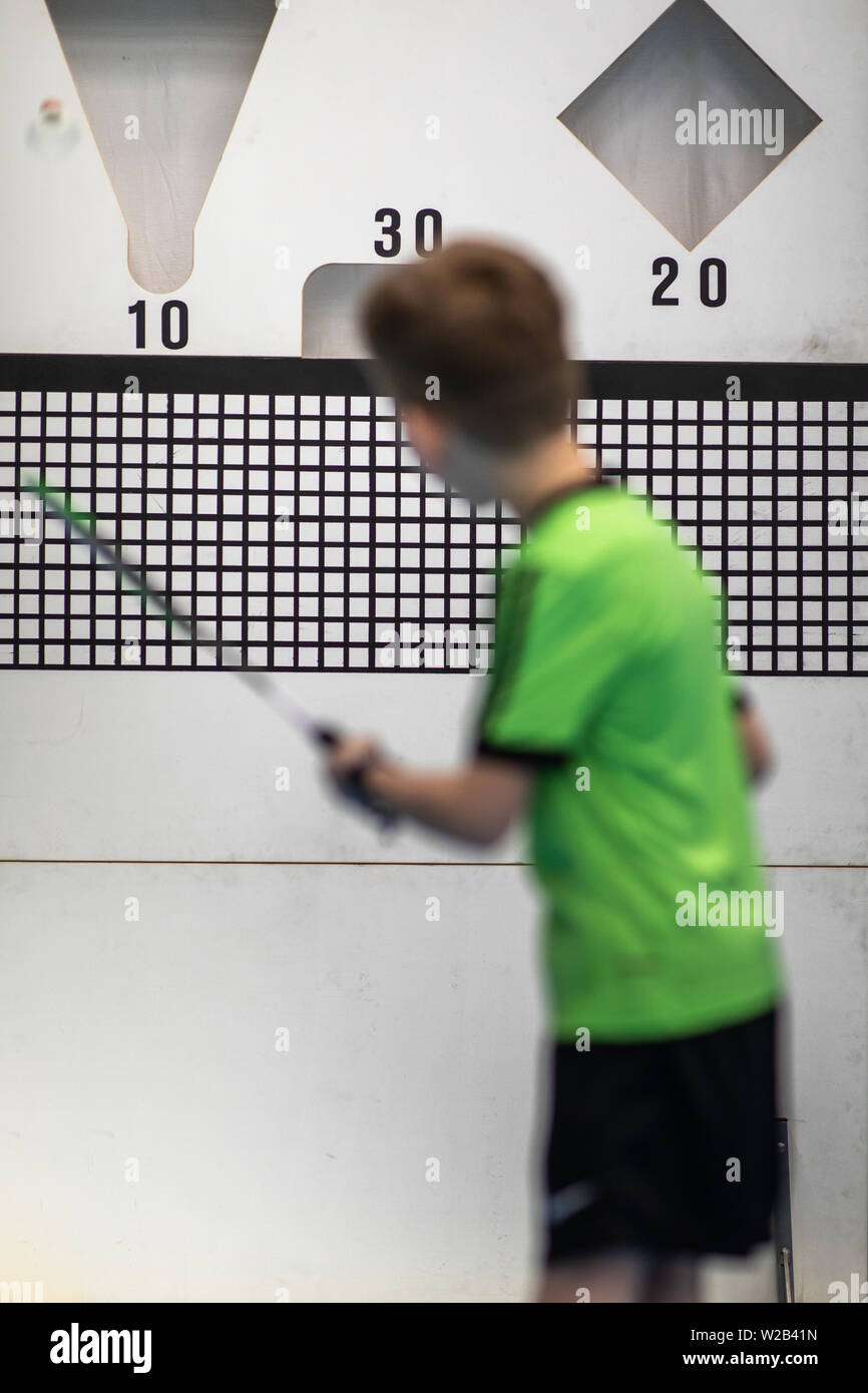 Young boy practising accurate badminton serve using targets during his