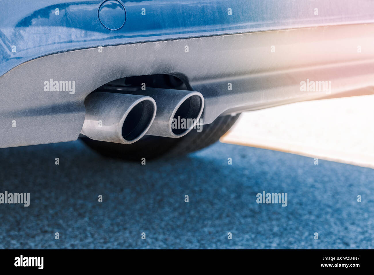 Closeup macro of dual double exhaust pipe. Detail of stylish blue car