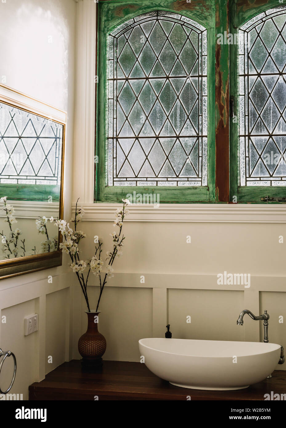 Bathroom with single sink and green restored double casement diamond pane window Stock Photo