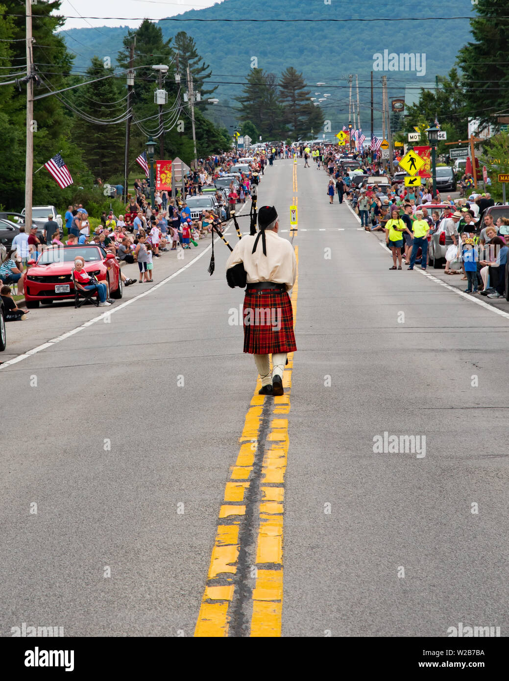 A highland bagpiper leading the 4th of July parade through Speculator, NY USA to the delight of the crowds gathered for the celebration. Stock Photo