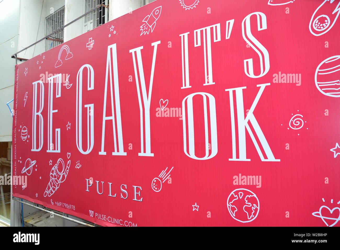 A sign advertising the Pulse health clinic and saying 'Be Gay  It's Ok' in the Silom tourist district of central Bangkok, Thailand Stock Photo