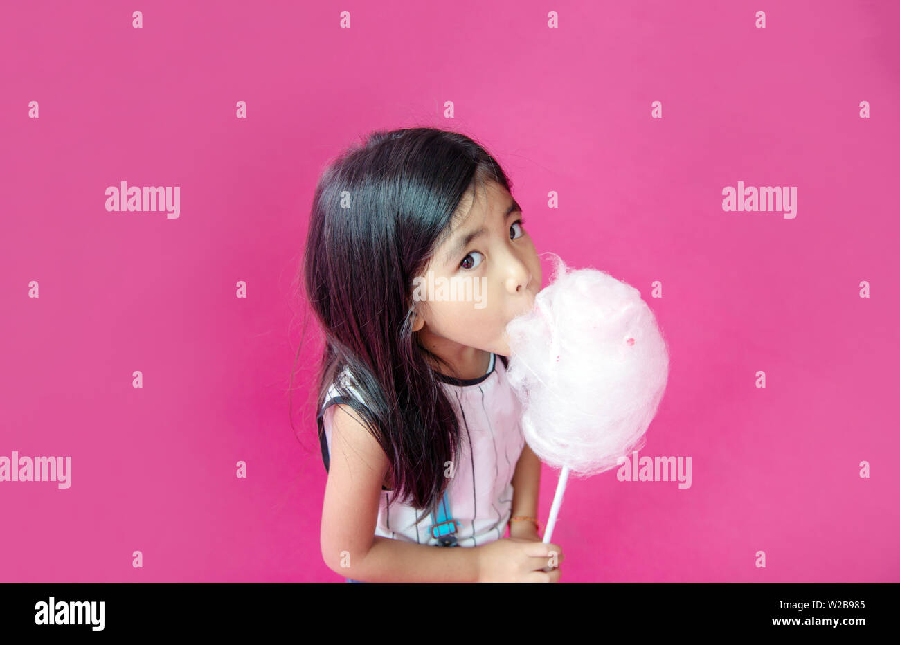 happy asian kid eating white candy cotton on pink background Stock Photo