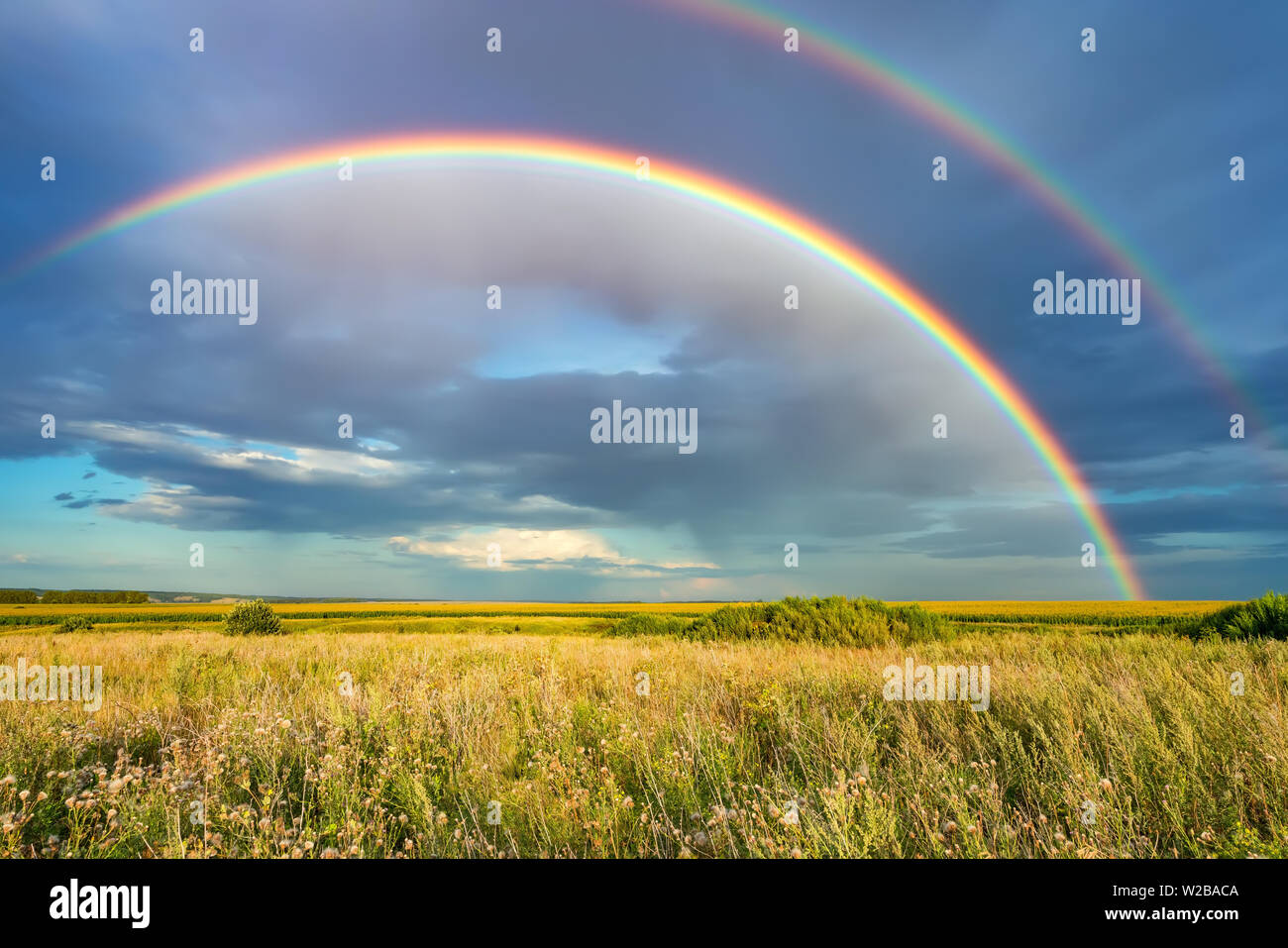 Rainbow over stormy sky in countryside at summer day Stock Photo