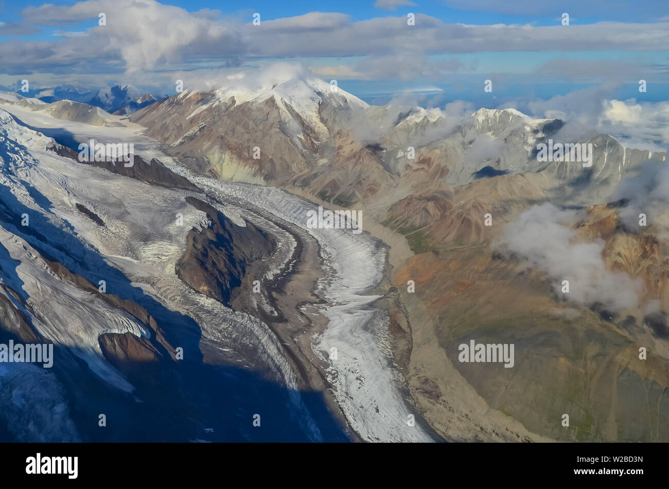 Aerial view of Alaska mountaion range around Denali peak from a plane with glaciers around and blue sky above. Denali National Park Stock Photo