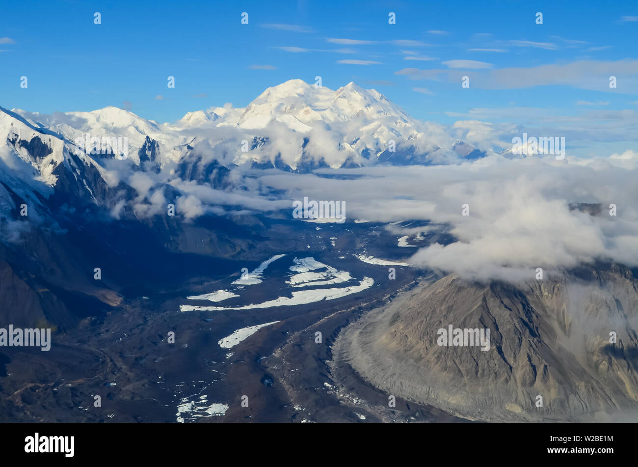 Aerial view of Alaska mountaion range around Denali peak from a plane with glaciers around and blue sky above. Denali National Park Stock Photo