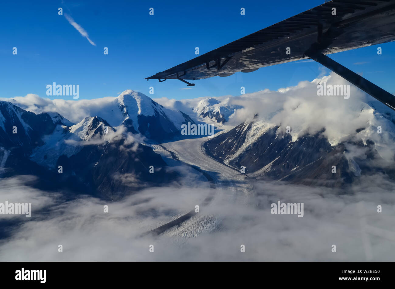 Aerial view of Alaska mountaion range around Denali peak from a plane with glaciers around and blue sky above. Denali National Park Stock Photo
