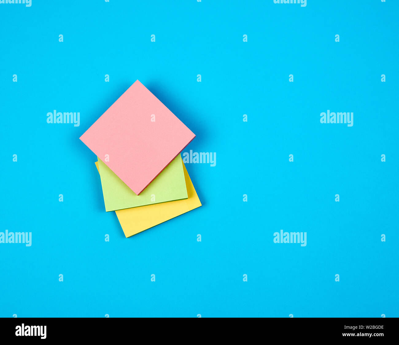 multicolored empty paper square stickers on blue background, copy space Stock Photo