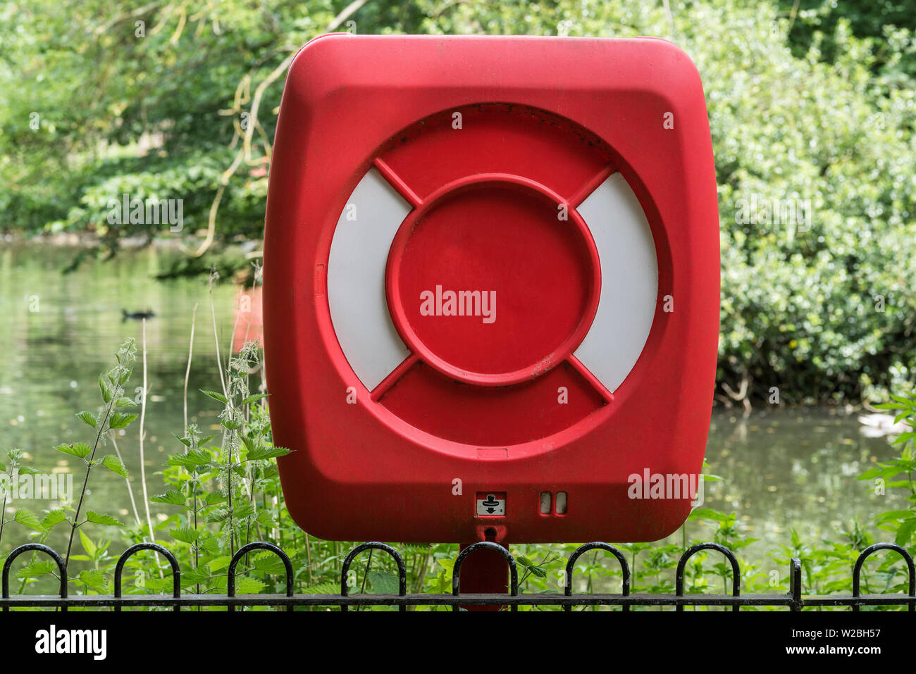 A life preserver station beside a lake in a park. Stock Photo