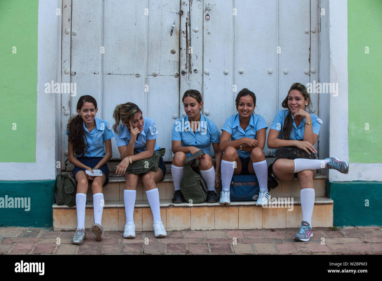 Cuba, Trinidad, School girls sitting on step in historical center Stock