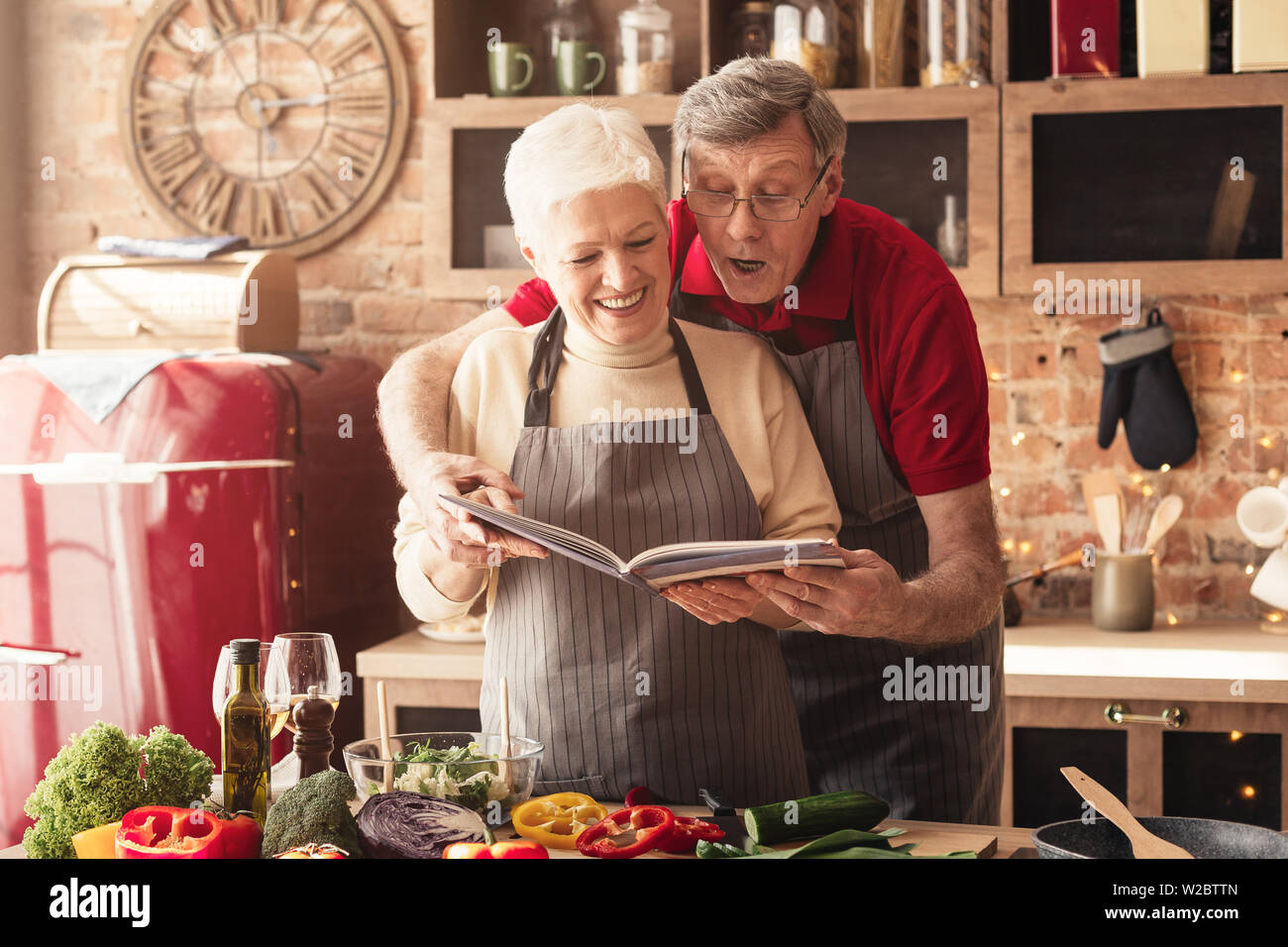 Senior couple preparing lunch with recipe book Stock Photo