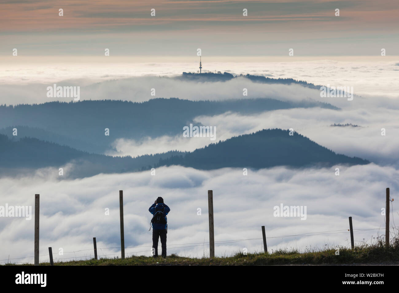 Germany, Baden-Wurttemburg, Black Forest, Belchen Mountain, summit view with evening fog and person Stock Photo