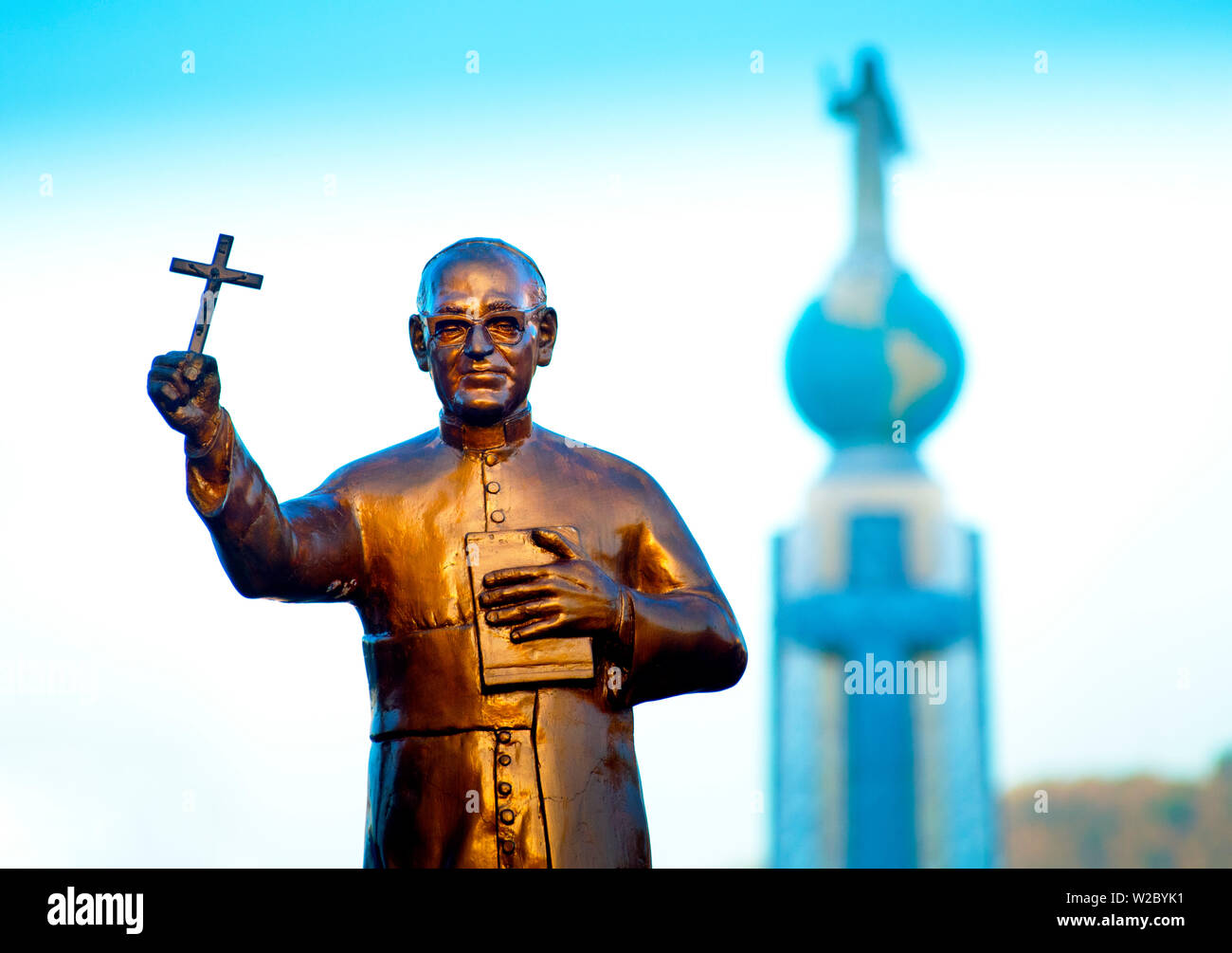 San Salvador, El Salvador, Dawn, Savior Of The World Plaza, Statue Of Archbishop Oscar Romero, Unofficial Patron Saint Of El Salvador, Assassinated At The Start Of The Country's Civil War In 1980, In The Background The Monument To The Divine Savior Of The World, Monumento Al Divino Salvador Del Mundo, Statue Of Jesus Christ Standing On A Global Sphere Of Planet Earth, Identifies And Represents El Salvador And Salvadorians Throughout The World Stock Photo