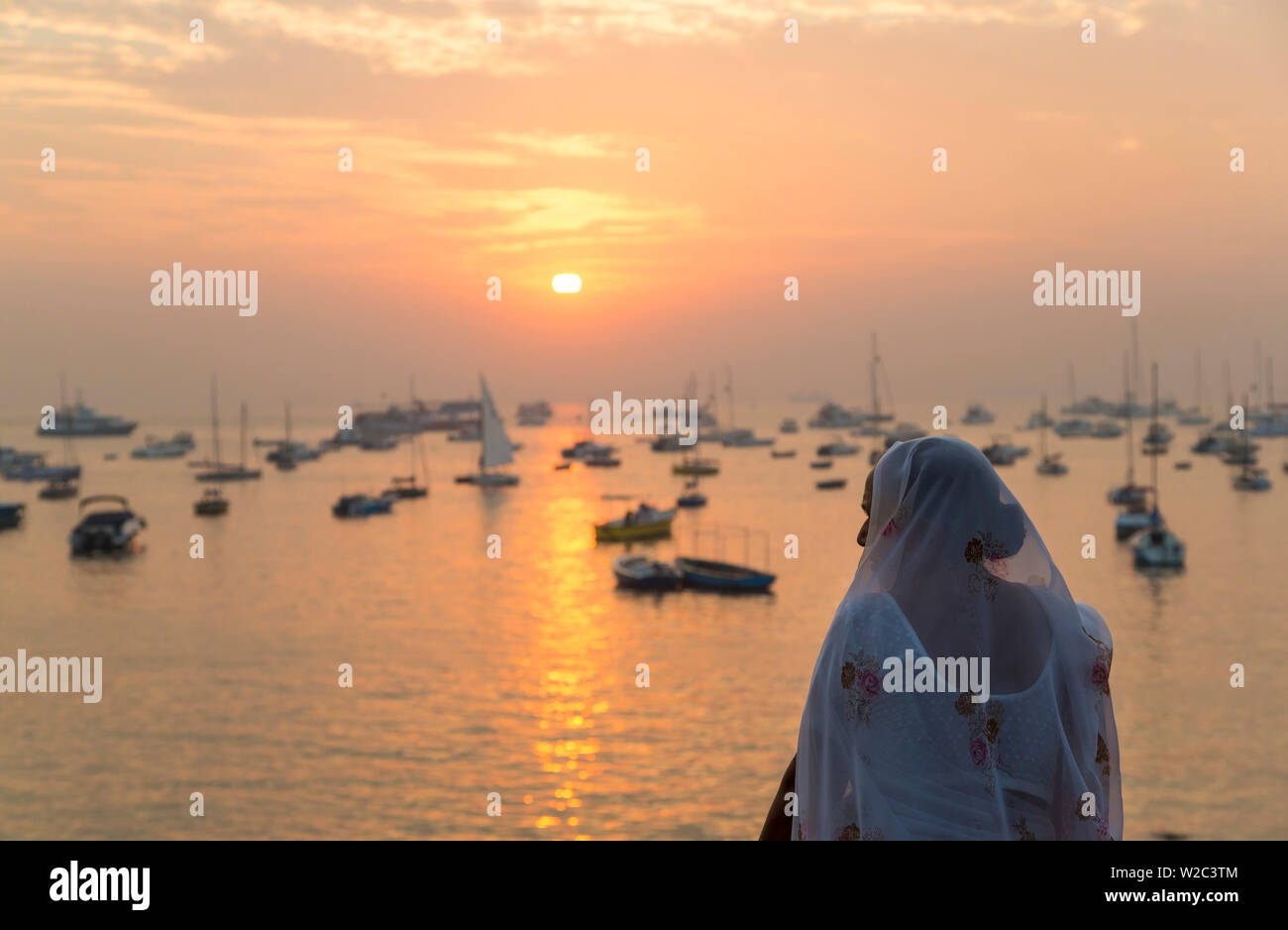 Indian woman looking out over Mumbai harbour by Gateway to India at sunrise, Mumbai, Bombay, India Stock Photo
