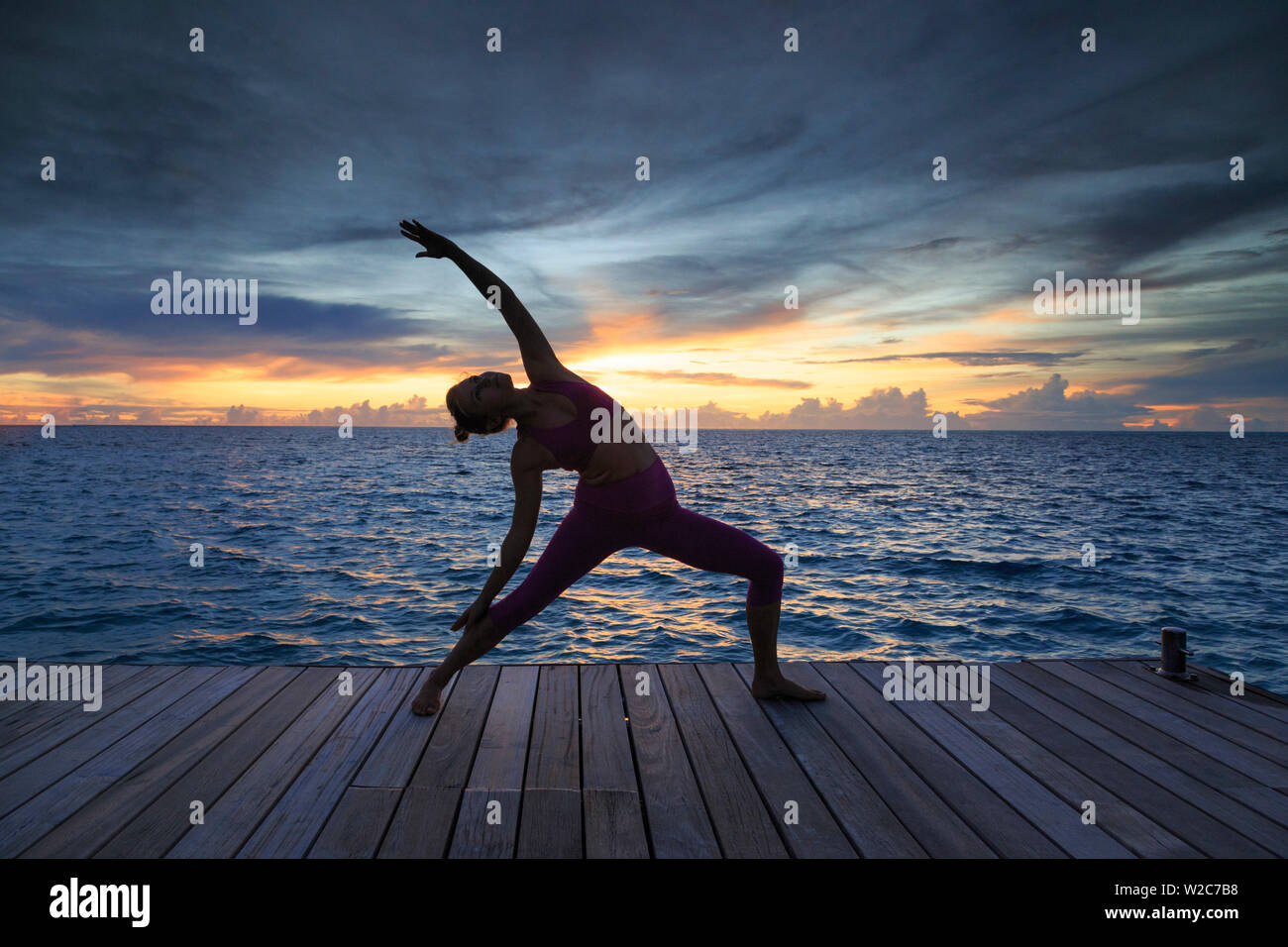 Maldives, South Ari Atoll, Thudufushi Island, Diamonds Thudufushi Resort, woman practising Yoga at sunset (MR) Stock Photo