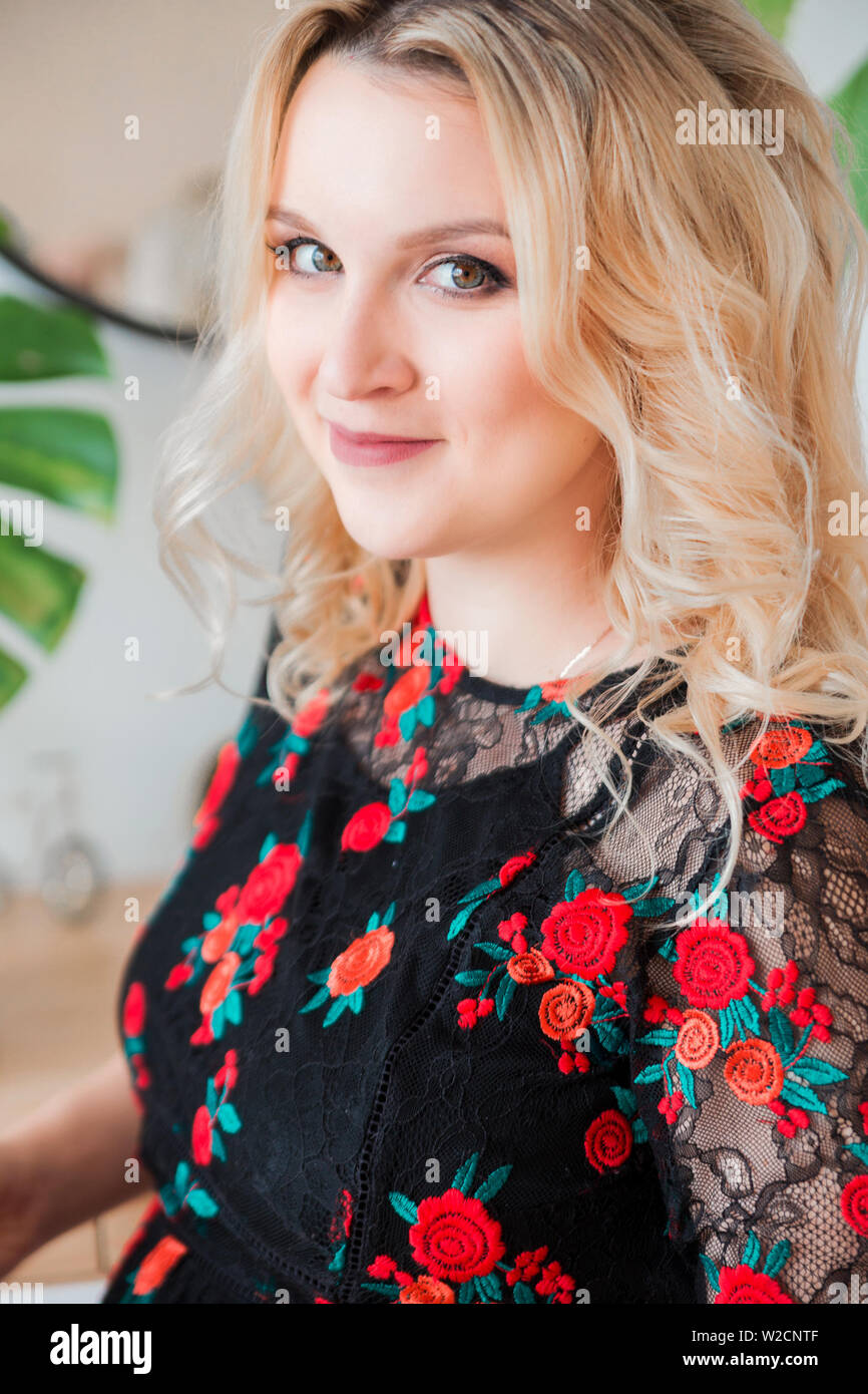 photo of blonde woman in black dress looking at camera and smiling Stock Photo